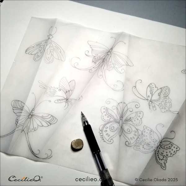 Folding the tracing paper to trace the second half of the butterflies.